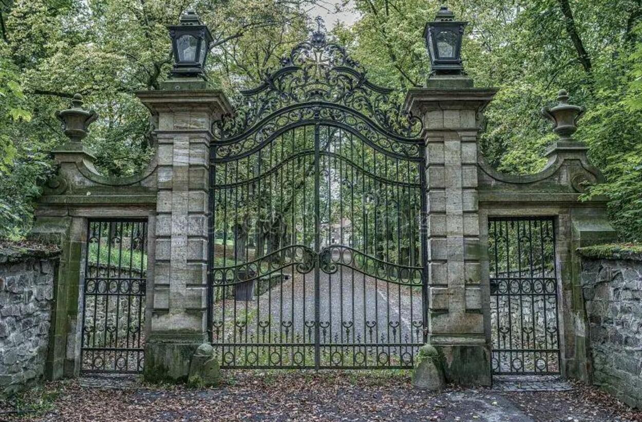 Ornate wrought-iron gate set within stone pillars and estate walls