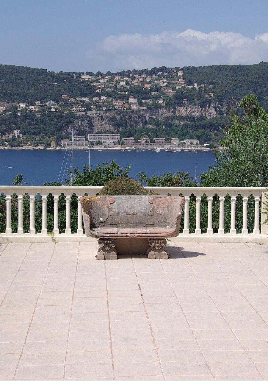 Pale stone terrace with a carved stone bench overlooking the Mediterranean coast